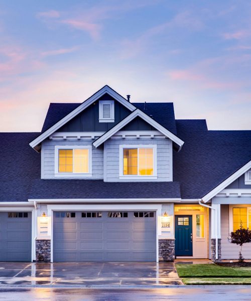 Beautiful two-story house with illuminated windows and garage at dusk.